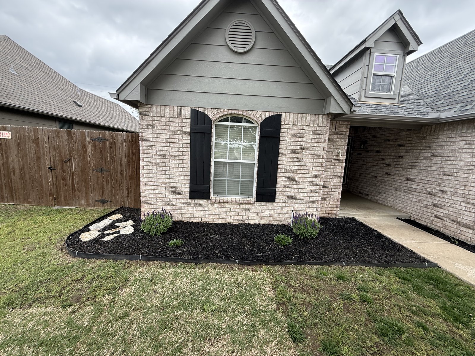 EllCo crisp black mulch bed and clean edging along a Tulsa brick home
