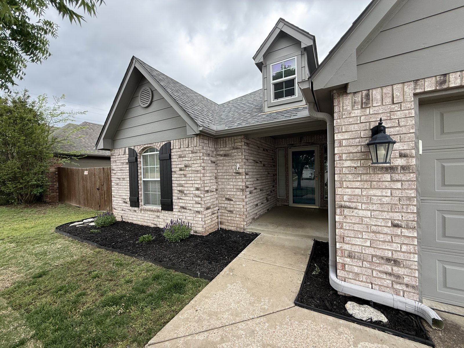 EllCo fresh mulch and an edged walkway wrapping a Tulsa brick home